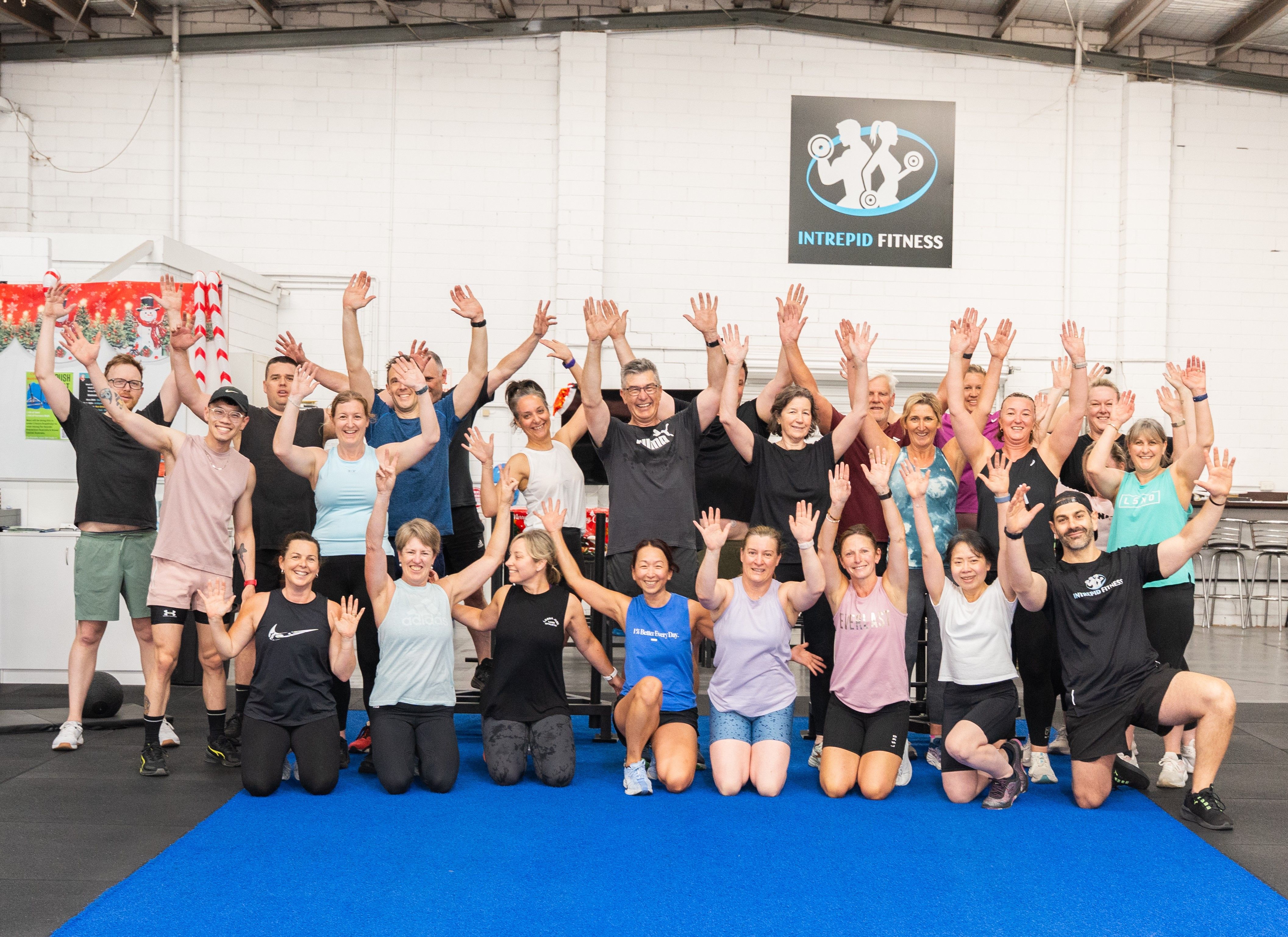 Large group training session on the blue turf at Intrepid Fitness with the gym sign visible